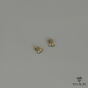 K&ouml;nnte beinhalten: Ein Paar Ohrstecker aus Gold und Silber mit einem kleinen Diamanten in der Mitte jedes Ohrsteckers.