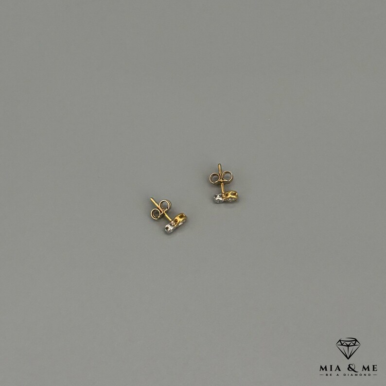 K&ouml;nnte beinhalten: Ein Paar Ohrstecker aus Gold und Silber mit einem kleinen Diamanten in der Mitte jedes Ohrsteckers.
