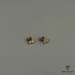 K&ouml;nnte beinhalten: Ein Paar Ohrstecker aus Gold und Silber mit zwei kleinen runden Diamanten in jedem Ohrstecker.