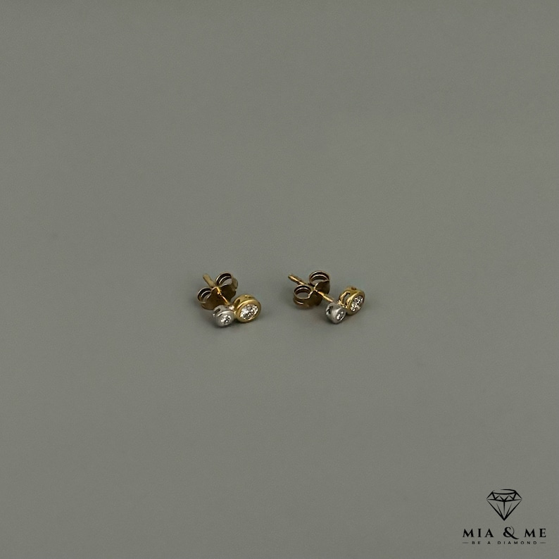 K&ouml;nnte beinhalten: Ein Paar Ohrstecker aus Gold und Silber mit zwei kleinen runden Diamanten in jedem Ohrstecker.