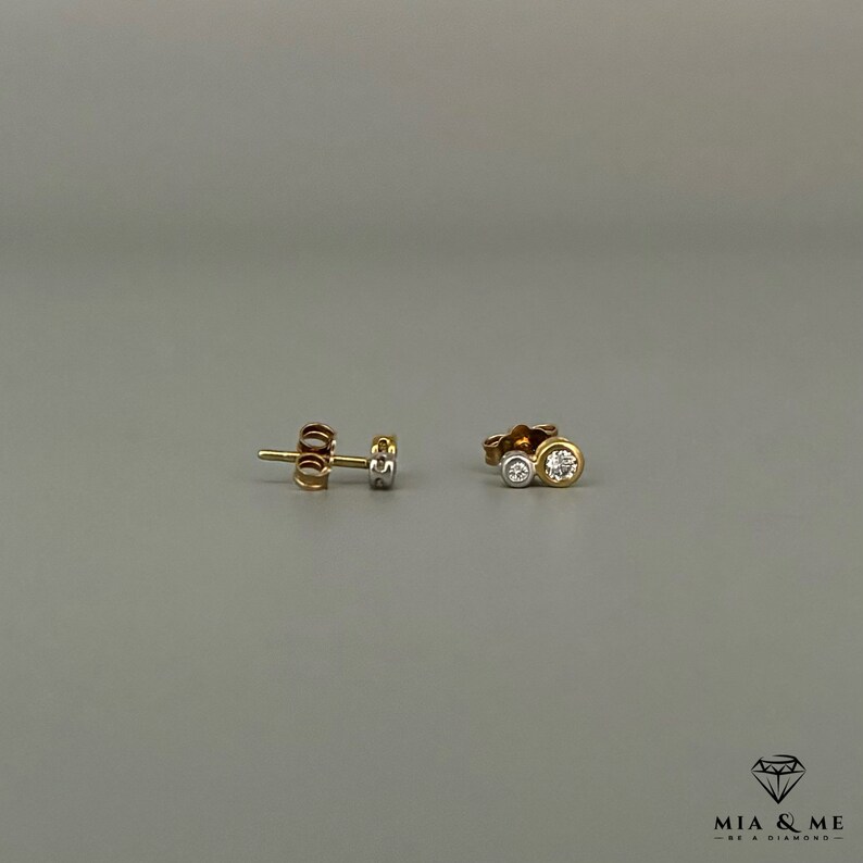 K&ouml;nnte beinhalten: Ein Paar Ohrstecker aus Gold und wei&szlig;en Diamanten. Die Ohrstecker haben zwei runde Diamanten, einer etwas gr&ouml;&szlig;er als der andere.