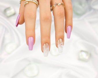 Op de afbeelding: Een hand met lange, amandelvormige nagels. De nagels zijn gelakt met een lichtroze en wit marmerpatroon. De hand draagt ​​meerdere gouden ringen.