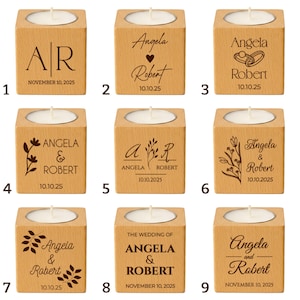 May include: A collection of nine wooden tea light candle holders. Each cube-shaped holder has a carved design and a space for a tea light candle. The designs include initials, names, dates, and floral elements, suitable for weddings or special events.