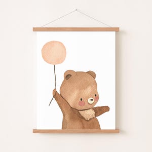 Peut inclure: Un ours brun tenant un ballon rose. L'ours sourit et a des joues roses. Le ballon est attaché à une ficelle.