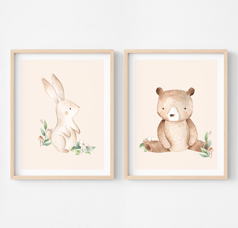 May include: Two framed prints with a watercolor illustration of a brown rabbit and a brown bear on a peach background. The rabbit is standing on its hind legs and the bear is sitting on a log. Both animals are surrounded by green leaves and pink flowers.