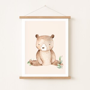 May include: A watercolor illustration of a brown bear sitting on a log with green leaves and pink flowers. The bear has a light brown nose and light brown fur.