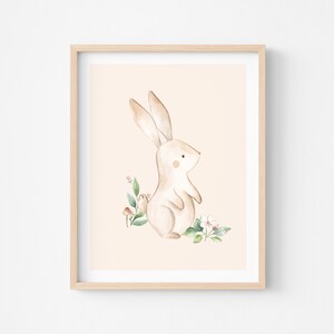 May include: A watercolor illustration of a brown bunny rabbit standing on its hind legs with its front paws raised. The bunny is surrounded by green leaves and pink flowers on a light peach background.