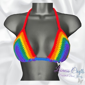 May include: A rainbow crochet halter top with a red strap. The top is made with a variety of colours, including red, orange, yellow, green, blue, indigo, and violet. The top is on a black mannequin.