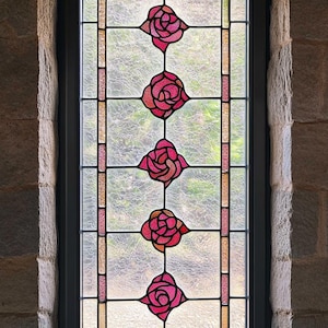 May include: A stained glass window with a black frame and five pink roses in a vertical pattern.