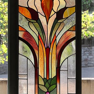 May include: A stained glass window featuring a floral design in shades of orange, yellow, green, and red. The design incorporates a central flower with leaves and stems.