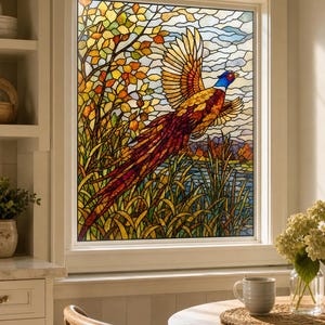 Peut inclure: Un panneau de fenêtre en vitrail représentant un faisan coloré en plein vol au-dessus d'un paysage herbeux avec un lac et des arbres d'automne. L'oiseau a une tête bleue, un contour d'œil rouge et des plumes dorées. Le ciel est nuageux.