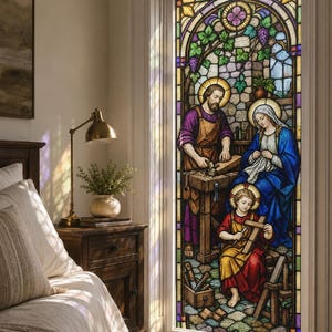 May include: A stained glass window panel depicting the Holy Family in a workshop. A man in a purple tunic works at a wooden bench, a woman in a blue robe sits nearby, and a child in a red tunic holds a wooden cross. The scene features grapevines.
