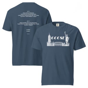 May include: Two navy blue t-shirts. The front shirt features a white graphic of the New York City skyline with the word "GOOSE" above it. The back shirt has a list of song titles in white text.