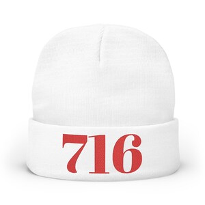 May include: A white beanie hat with a folded-up brim. The number "716" is embroidered in red on the front. The hat is made of a soft, knitted material.