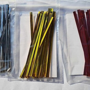 May include: Three bags of metallic twist ties. The bags are clear plastic and contain silver, gold, and red twist ties.