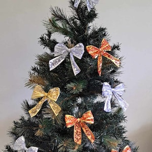 May include: An artificial Christmas tree decorated with silver, gold and red bows. The bows are made from shiny, patterned ribbon.