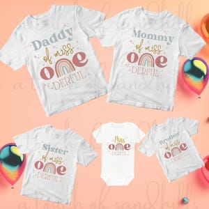 May include: Set of five white t-shirts with rainbow and star designs. The shirts say "Daddy of miss one DERFUL", "Mommy of miss one DERFUL", "Sister of miss one DERFUL", "Miss one DERFUL", and "Brother of miss one DERFUL".