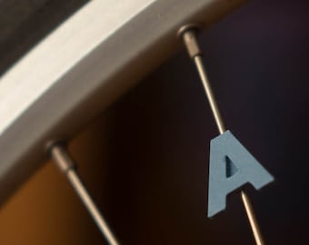 Bike Spoke Decoration Letter "A". Fits on bicycle wheel spokes. This accessory clips onto bike spokes like a spoke bead. Made in USA.