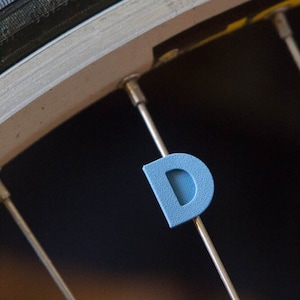 Letter &quot;D&quot; Bike Spoke Decoration. Fits on bicycle wheel spokes. This accessory clips onto bike spokes like spoke beads. Made in USA.