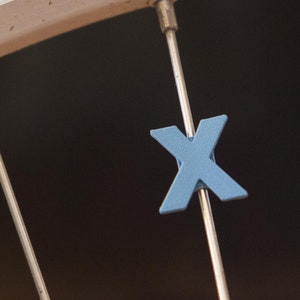 Letter &quot;X&quot; Bike Spoke Decoration. Fits on bicycle wheel spokes. Accessory clips onto bike spokes like spoke beads. Made in USA.