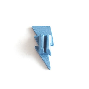May include: A light blue plastic lightning bolt shaped phone stand.