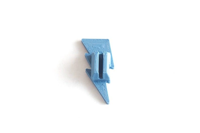May include: A light blue plastic lightning bolt shaped phone stand.