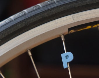 Letter "P" Bike Spoke Decoration. Fits on bicycle wheel spokes. Accessory clips onto bike spokes like spoke beads. Made in USA.