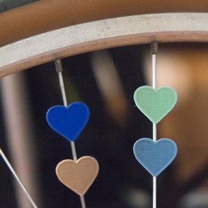 4 pack Heart bike spoke decoration for bicycle wheels. Colors available, like spoke charms beads. Bike accessory clips on spokes.