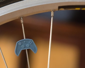 Video game controller bike spoke decoration. Fits on bicycle wheel spokes. Accessory clips on bike spokes like spoke beads. Made in USA