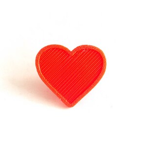 May include: A red heart-shaped object made of plastic with a textured surface.