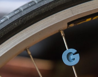 Letter "G" Bike Spoke Decoration. Fits on bicycle wheel spokes. Accessory clips onto bike spokes like spoke beads. Made in USA.