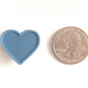 May include: A blue heart-shaped object with a textured surface, next to a US quarter.