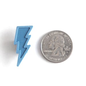 May include: A light blue lightning bolt shaped charm, approximately the size of a US quarter.