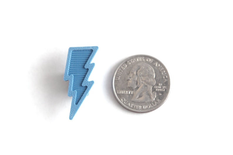 May include: A light blue lightning bolt shaped charm, approximately the size of a US quarter.