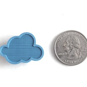May include: A small, light blue cloud-shaped object made of plastic. The object is about the size of a US quarter.