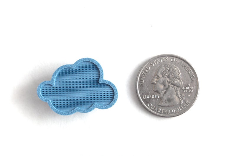 May include: A small, light blue cloud-shaped object made of plastic. The object is about the size of a US quarter.