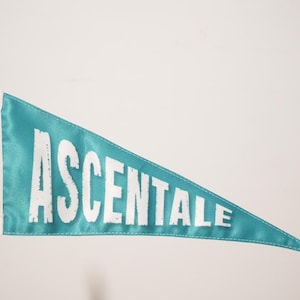May include: A teal blue pennant flag with the word "ASCENTALE" printed in white.