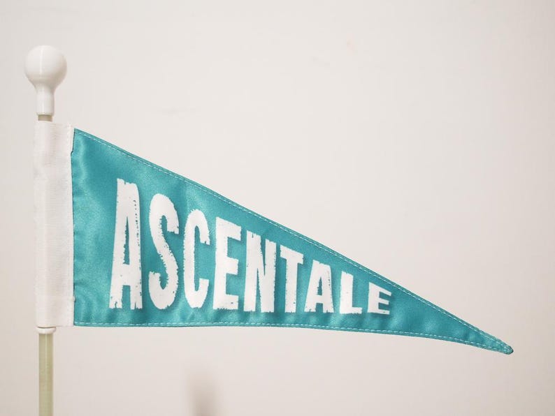 May include: A teal blue pennant flag with the word "ASCENTALE" printed in white.