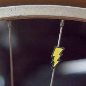 Lightning bolt bike spoke decoration. Fits on bicycle wheel spokes. Accessory clips on bike spokes like spoke beads. Made in USA
