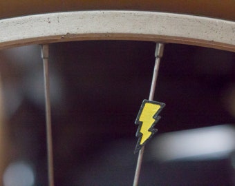 Lightning bolt bike spoke decoration. Fits on bicycle wheel spokes. Accessory clips on bike spokes like spoke beads. Made in USA