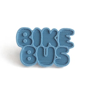 May include: A blue 3D printed pin with the text "Bike Bus" in a retro font.