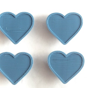 May include: Four blue heart-shaped objects with a textured surface.