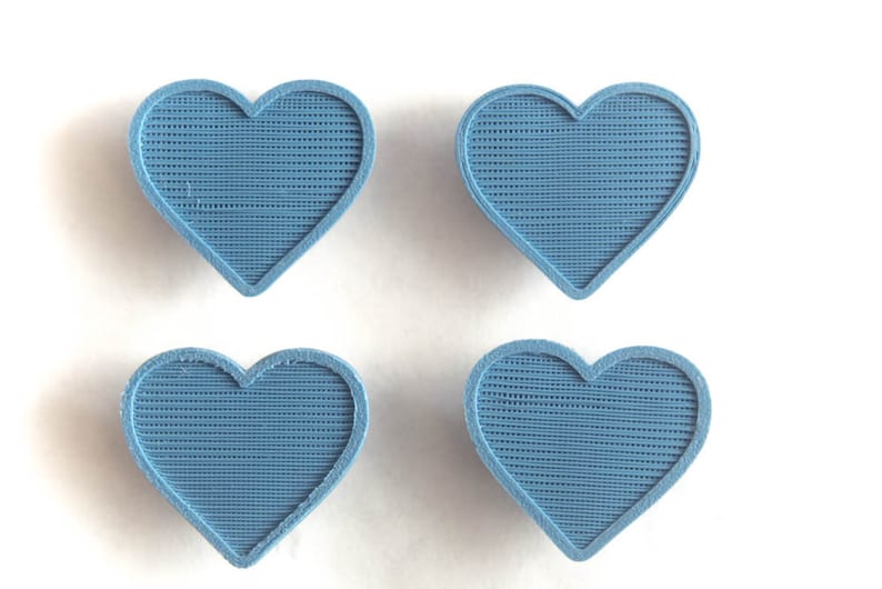 May include: Four blue heart-shaped objects with a textured surface.