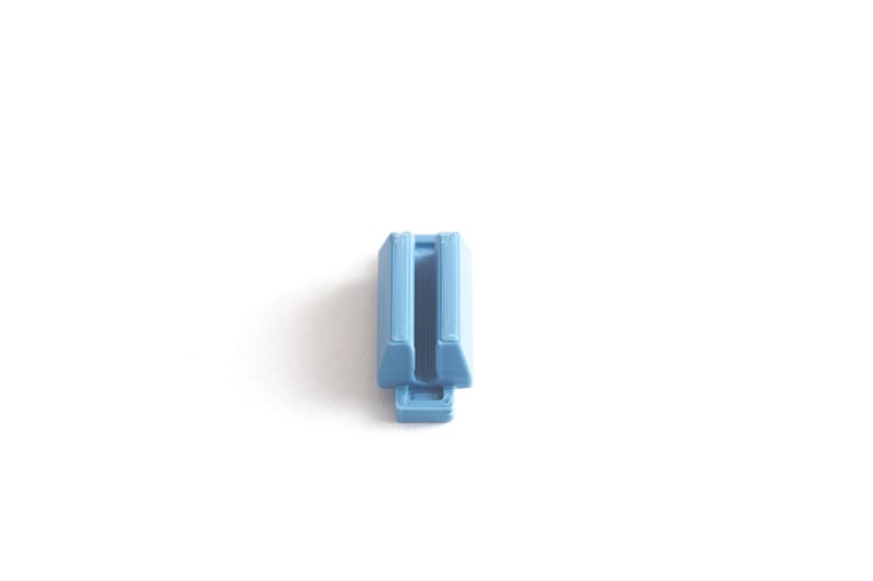 May include: A light blue plastic connector with a slot in the middle.