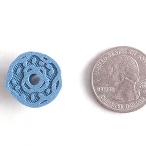 Peut inclure: Un objet en plastique bleu en forme de beignet avec un trou au centre. L'objet est &agrave; peu pr&egrave;s de la taille d'une pi&egrave;ce de 25 cents am&eacute;ricaine.