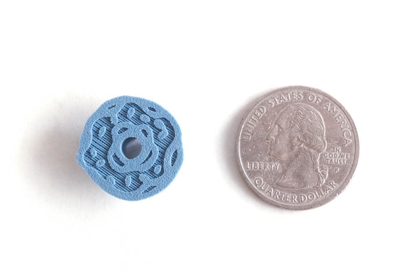Peut inclure: Un objet en plastique bleu en forme de beignet avec un trou au centre. L'objet est &agrave; peu pr&egrave;s de la taille d'une pi&egrave;ce de 25 cents am&eacute;ricaine.