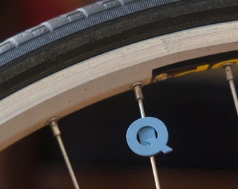 Letter "Q" Bike Spoke Decoration. Fits on bicycle wheel spokes. Accessory clips onto bike spokes like spoke beads. Made in USA.