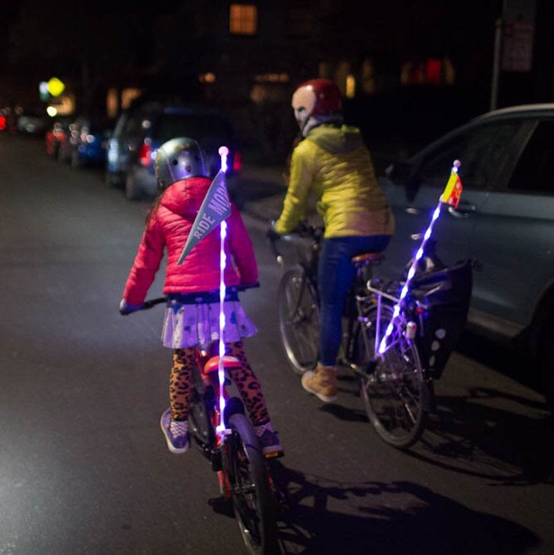 Two bicycle riders with light up LED glow sticks attached to their bikes.