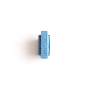 May include: A small, light blue plastic tile with a raised, textured surface.