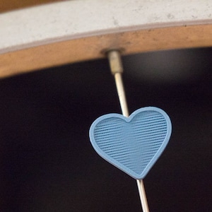 Pu&ograve; includere: Un ciondolo a forma di cuore blu appeso a un raggio di una ruota di bicicletta.